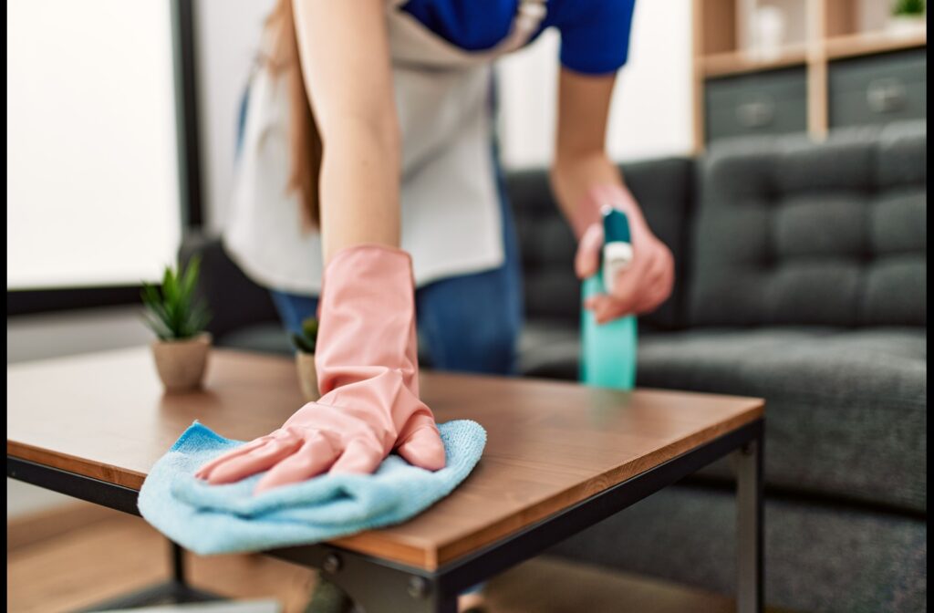 A professional cleaner dusting a table in a commercial office space