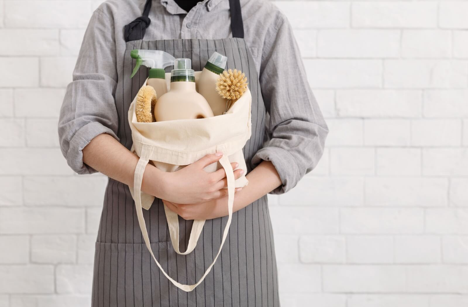 A house cleaner holding a bag of eco-friendly cleaning products