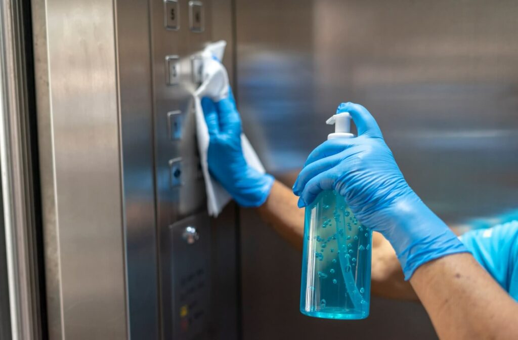 A professional cleaner wipes down the buttons in an elevator.