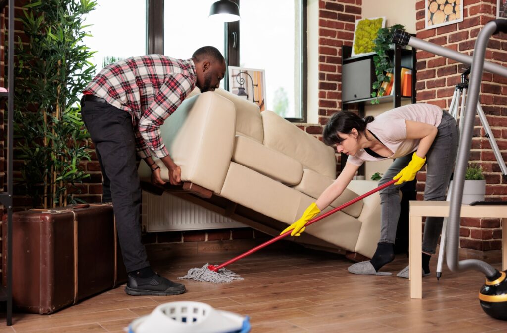 A couple mopping under the sofa for their spring clean.