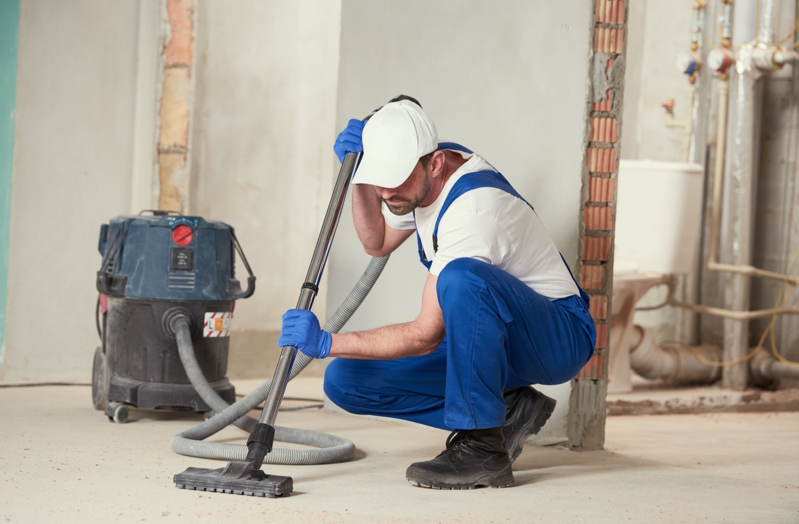 A professional cleaner uses an industrial vacuum to clean a home construction site.