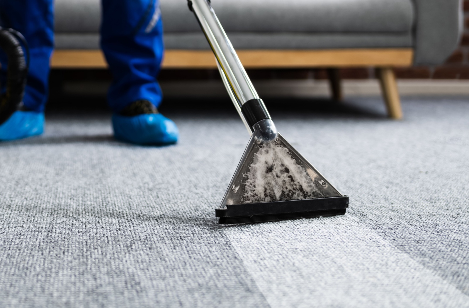 An image of a professional carpet cleaner being used to clean a carpet, showing a visibly cleaner section where the machine is being utilized.