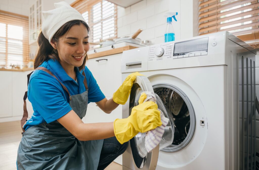 A professional cleaner wipes down the washing machine door during a deep clean.