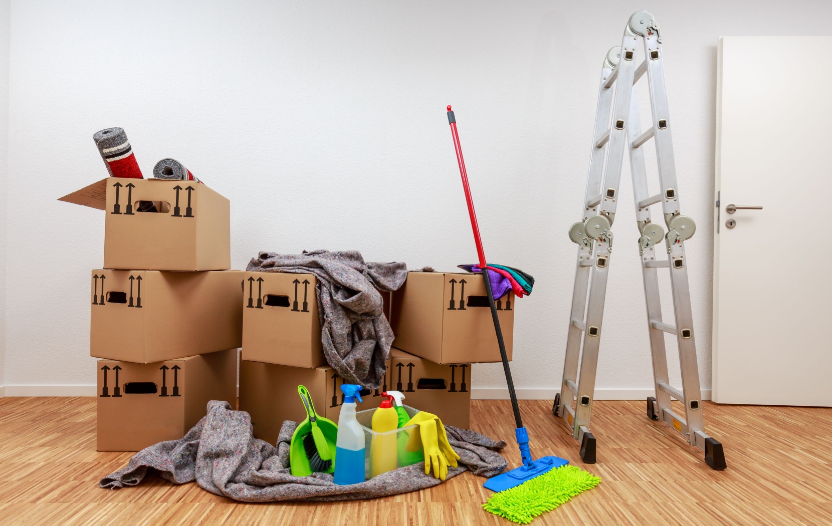 A pile of cleaning supplies sit in the middle of a brand-new room. All the debris has been removed and every corner meticulously cleaned.