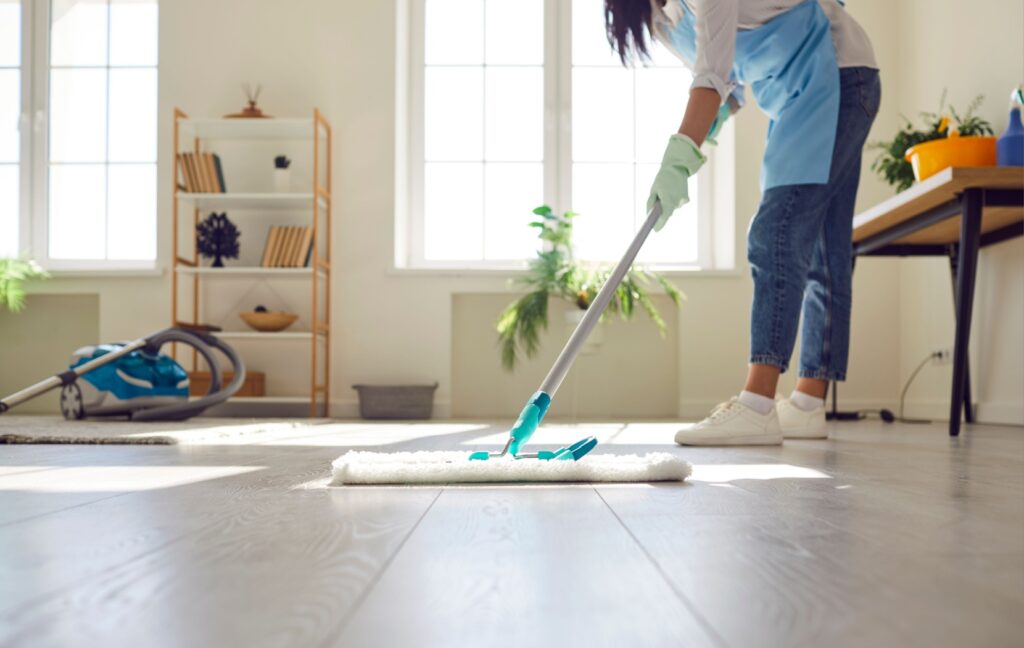 A professional cleaner uses a mop and high-quality cleaning products to clean the floor of a client's apartment.