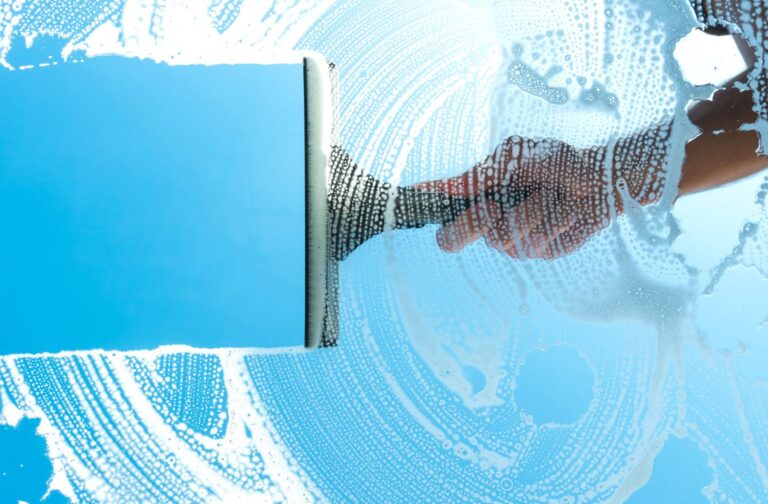 A squeegee leaves a clean strip on a soapy window.